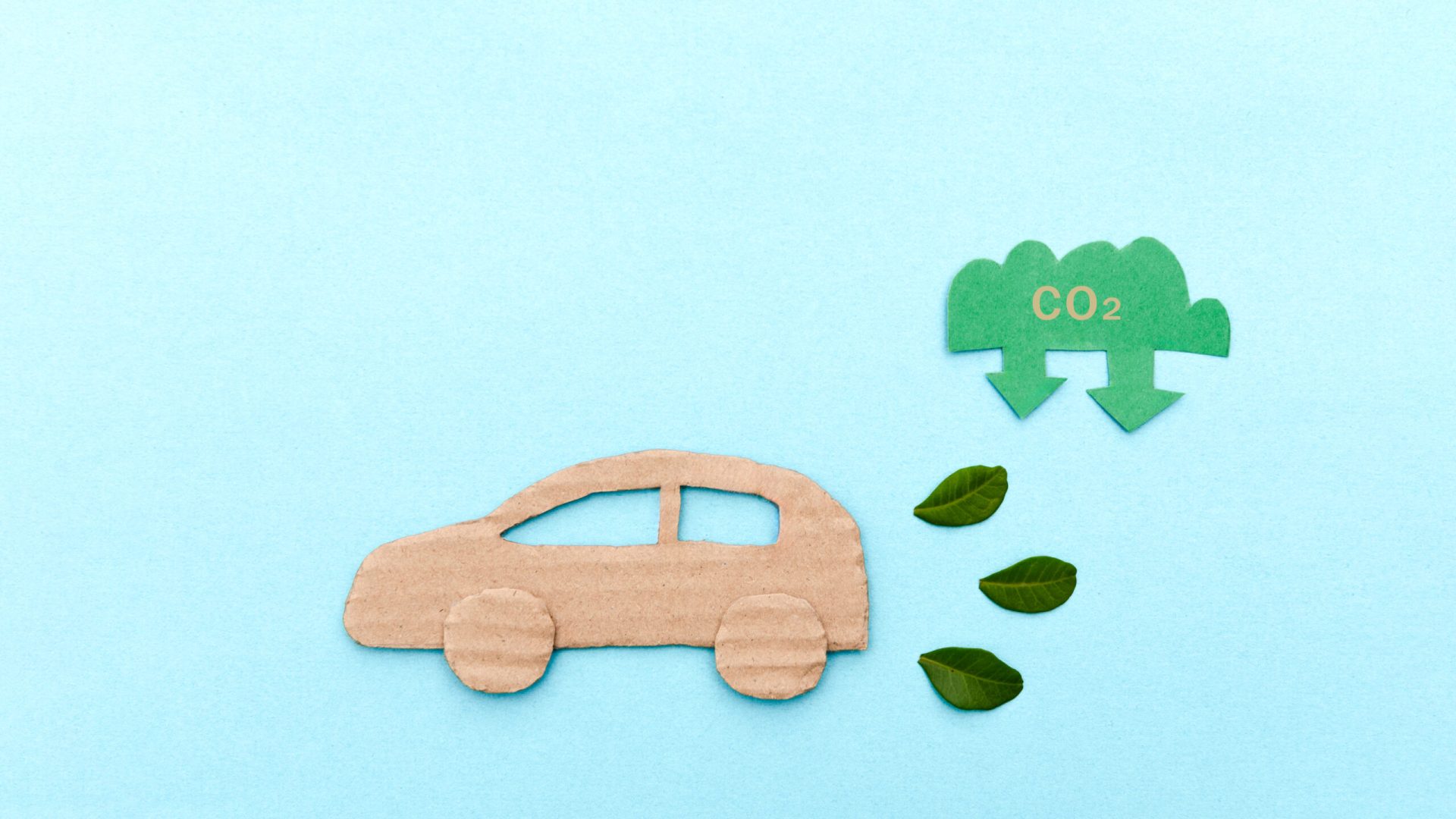 Environmental Awareness Concept with Cardboard Car, CO2 Symbol and Green Leaves on Blue Background, low emissions and eco friendly transportation